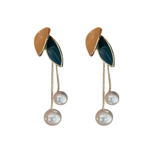 Retro vintage earrings with orange green leaves and faux pearl tassels on white background