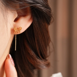 Detail of vintage gold plated butterfly threader earring on model with tassels