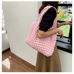 Side view of pink puffy cloud shoulder bag featuring textured popcorn fabric on a model