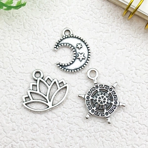 Detail of silver alloy charms featuring moon stars, lotus, and helm on white background