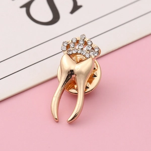 Spilla a forma di dente in oro rosa con corona di strass e chiusura a farfalla