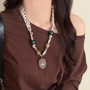 Detail of leopard print ribbon necklace with resin beads and wooden planet pendant