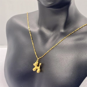 Detailed view of a golden balloon dog pendant necklace on a professional black bust display