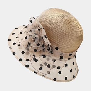 Detail of elegant beige sun hat featuring organza flower and black polka dot mesh trim