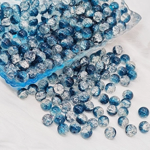 Macro view of blue crackle glass beads on white fabric for DIY jewelry making