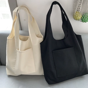 Detail of plain canvas tote bags in cream and black on a sofa with natural texture