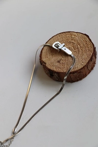 Dettaglio di collana a catena serpente argento con chiusura a fibbia su base in legno