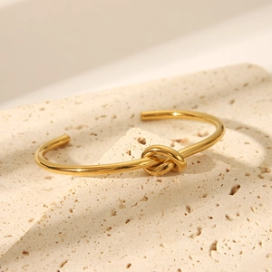 Detailansicht eines goldenen Knotendesigns auf einem polierten Edelstahl-Armreif