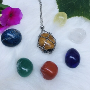 Tiger eye crystal stone pendant wrapped in silver wire on a plush background with flowers