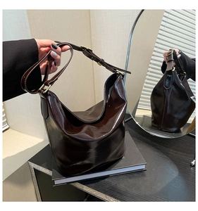 Detail of dark brown glossy leather handbag with gold buckles and adjustable strap