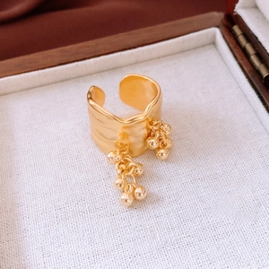 Detail of 18K gold plated wide ring featuring irregular wrinkles and tassel bead charms