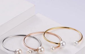 Detailed view of minimalist open bracelets in gold, silver, and rose gold with twin pearls