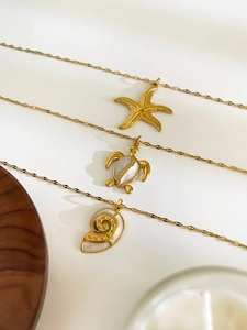 Detail view of 18K gold star, turtle, and shell necklaces with mother of pearl inlays
