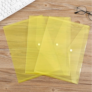 Set of three yellow transparent A4 plastic file folders with snap button on wood desk