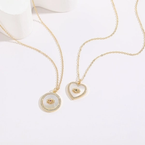 Macro shot of 14K gold-plated heart and round necklaces with shell evil eye charms