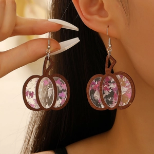Detail of Halloween pumpkin earrings with wood frame and purple star sequins on ears