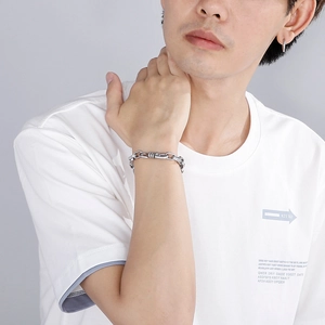 Detail view of vintage stainless steel square buckle bracelet and silver hoop earring on model
