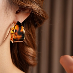 Detail view of tortoiseshell resin hoop earrings with gold-plated metal trim on model