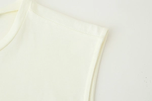 Gros plan détaillé des coutures d'épaules et de la texture fine de la robe en coton beige