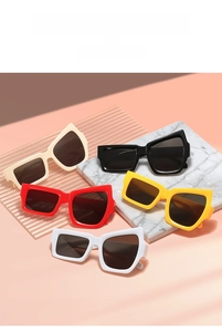 Lunettes de soleil irrégulières en crème, noir et rouge sur fond de marbre élégant