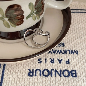 Close-up of double layer silver rings on vintage coffee cup with Bonjour embroidery