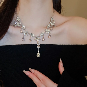 Detail of silver drop fringe necklace with clear crystals worn by a model in black