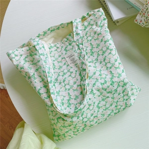 Detailed top view of a floral canvas tote bag with a woven label on a white desk