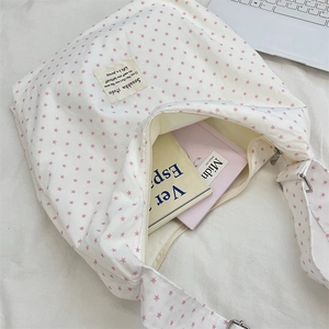 Close-up of white canvas tote with pink star prints and adjustable strap for commuting