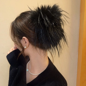 Gros plan d'une pince à cheveux noire en plumes duveteuses sur les cheveux d'un modèle
