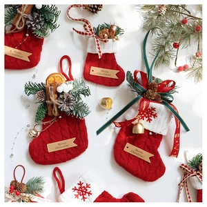 Close-up of red Christmas stocking with pine cones, cinnamon, and golden bell detail