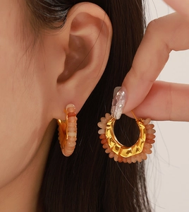 Detail of C-shaped titanium earrings with colorful natural stones and warm gold finish
