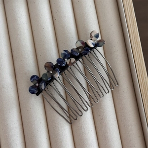 Detail of flower hair clip with blue and brown marble pattern on beige jewelry box