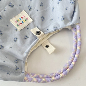 Dettaglio della borsa floreale con manici in corda colorata e chiusura con bottone in metallo