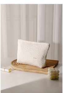 Detail of cream white cosmetic bag with textured bubble fabric and H&R brand label