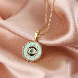 Detailed macro view of gold evil eye pendant necklace on elegant pink silk background