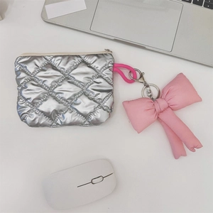 Detail of silver quilted heart coin purse with pink fabric bow keychain on desk