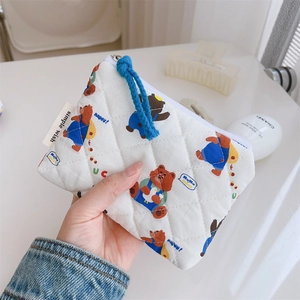 Détail de la pochette matelassée aux motifs d'ours, fermeture éclair bleue et étiquette