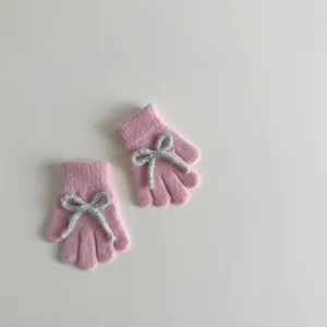 Detail of pink knitted gloves featuring a soft blue bow accent and warm plush texture