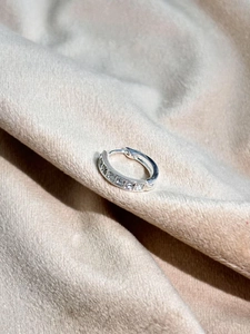 Macro view of silver ear hoops featuring square channel-set cubic zirconia stones
