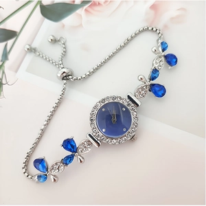 Elegant silver leaf watch with blue dial and clover crystal charms on a floral background
