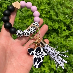 Detail of mama cow head charm on silicone bead bracelet with leopard cow print tassel