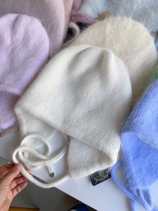 Nahaufnahme von flauschigen Angora-Hasenhaar-Mützen mit Ohrenklappen in Macaron-Farben