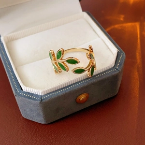 Detailed close-up of golden olive leaf ring with green enamel finish in a velvet box
