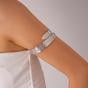 Detail shot of a silver geometric镂空 carved armlet on a model's upper arm