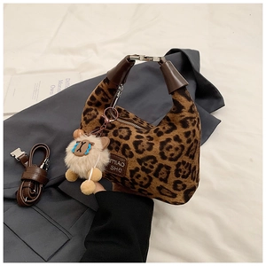Detail of leopard print handbag with brown leather strap and alpaca charm on grey blazer
