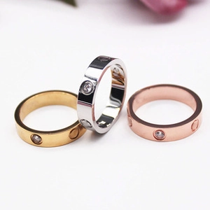 Close-up of gold, silver, and rose gold rings with small inlaid crystals on a white surface
