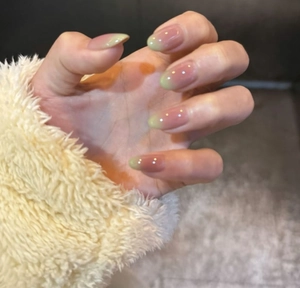 Detail of light green gradient French manicure on oval press-on nails with glossy finish