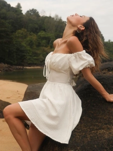 Weißes Off-Shoulder-Kleid mit Puffärmeln und Taillenzug in einer Strandlandschaft
