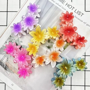 Five colorful gradient flower hair claws arranged on a book with stylish matte finish