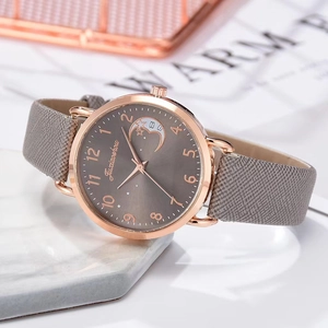 Detail of rose gold quartz watch featuring a crescent moon dial and grey leather strap